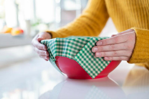 beeswax wrap being used to seal a container